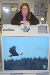 Toni Falk, Land Use Clerk Technician is pictured with one of the multibin recycling bins that features her photo.